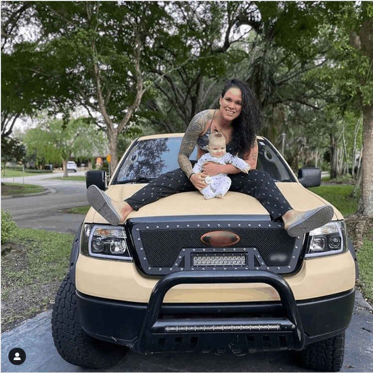 Amanda Nunes posing with her baby on the car.