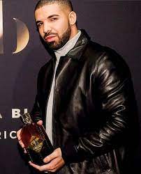 Drake in his black leather poses with a whisky